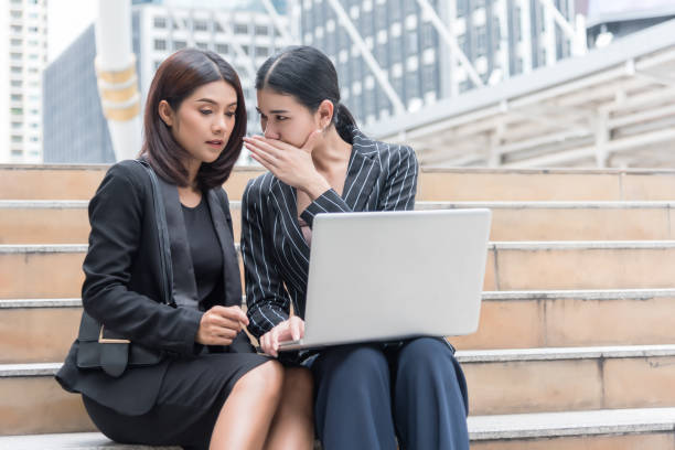 Business women gossip while using laptop at outdoor. Business and coworker concept